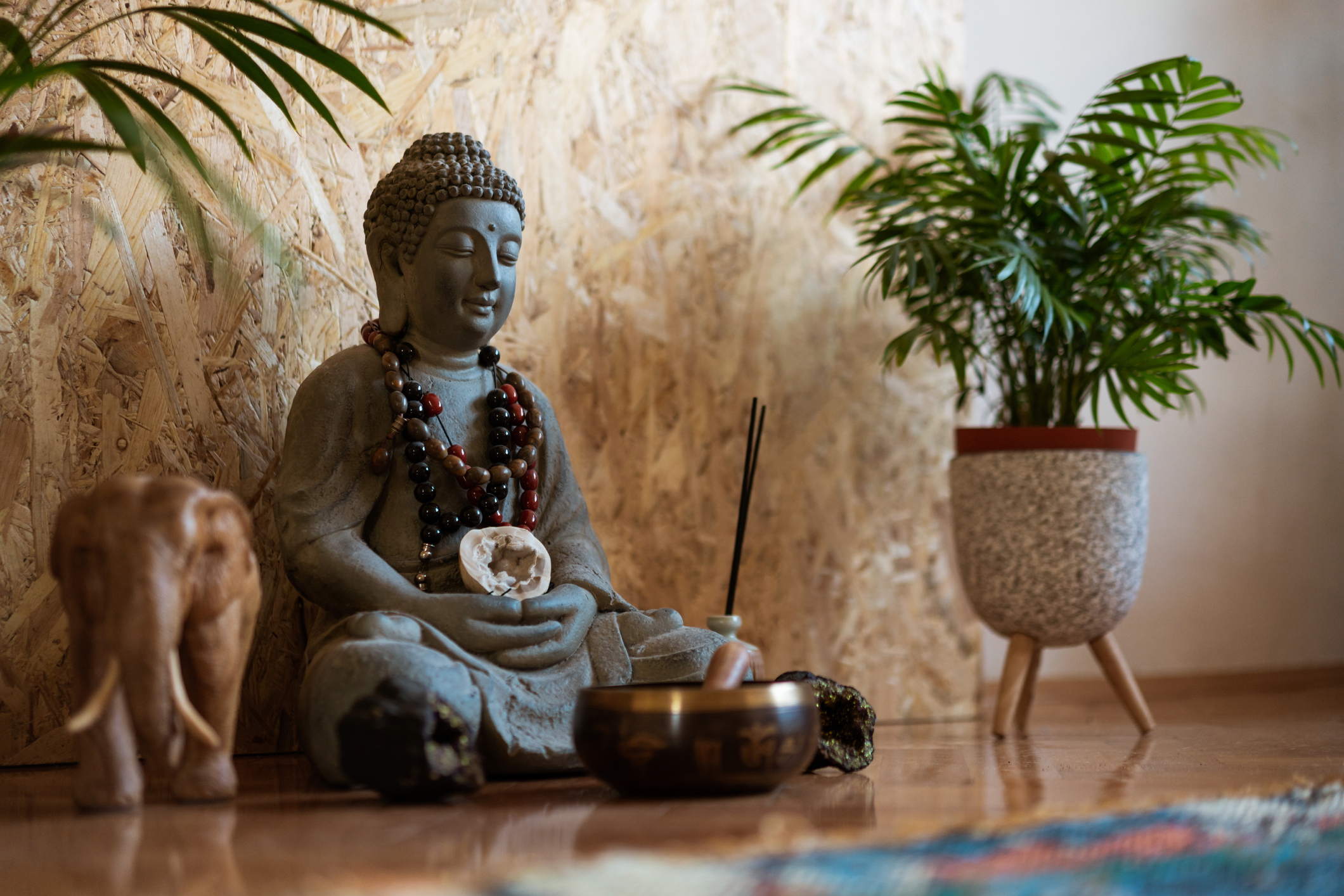 Statue of Buddha and a small meditation bell on the floor.